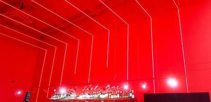 phuket, Thailand - maart 2, 2022 modern interieur ontwerp met verlichting en alcohol drinken Aan plank. rood muur en plafond met neon en spotlight ingericht. foto