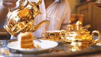 dichtbij omhoog van vrouw hand- gieten gouden luxe theepot reeks in de cafe of restaurant foto