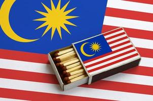 Maleisië vlag is getoond in een Open luciferdoosje, welke is gevulde met wedstrijden en leugens Aan een groot vlag foto