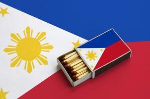 Filippijnen vlag is getoond in een Open luciferdoosje, welke is gevulde met wedstrijden en leugens Aan een groot vlag foto