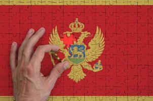 Montenegro vlag is afgebeeld Aan een puzzel, welke de man's hand- voltooit naar vouwen foto