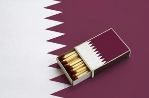 qatar vlag is getoond in een Open luciferdoosje, welke is gevulde met wedstrijden en leugens Aan een groot vlag foto