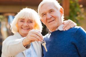 leven is alleen maar begin. gelukkig senior paar bonding naar elk andere en glimlachen terwijl vrouw Holding sleutels in haar hand- foto