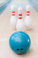 pinnen en bal zijn Super goed team. detailopname van blauw bowling bal aan het liegen tegen pinnen blijven Aan bowling steeg foto