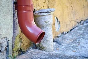 rood water afvoer Aan een straat van een klein stad bestrating in de buurt geel muur foto