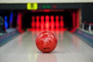 bereiken de doel. detailopname van helder rood bowling bal rollend langs bowling steeg foto