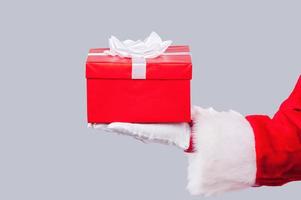 geschenk doos. detailopname van de kerstman claus Holding geschenk doos tegen grijs achtergrond foto