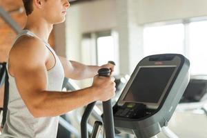 cardio oefening. bijgesneden beeld van knap jong Mens aan het doen cardio oefening Aan stap machine foto