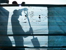 een arbeider werken met Schep achter de blauw kleding stof hek foto