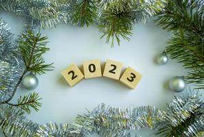 kubussen met de opschrift 2023, Kerstmis boom takken, klatergoud en Kerstmis ballen. foto