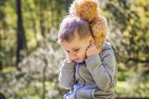 een schattig jongen is spelen met een beer welp in de Woud. de zon stralen omhullen de ruimte van de opruimen met een stomp. een magisch verhaal van interacties voor de boek. ruimte voor kopiëren. selectief foto