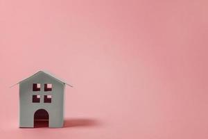 eenvoudig ontwerp met miniatuur wit speelgoed- huis geïsoleerd Aan roze pastel kleurrijk modieus achtergrond. hypotheek eigendom verzekering droom huis concept. kopiëren ruimte. foto