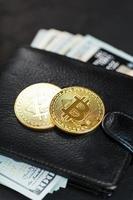 een zwart portemonnee met dollar, e-kaarten en bitcoins Aan een zwart getextureerde achtergrond. foto