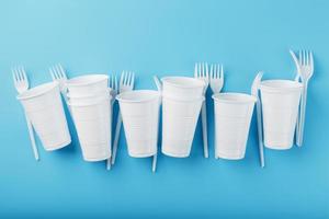plastic serviesgoed Aan een blauw achtergrond. beschikbaar vorken en bril met vrij ruimte. foto