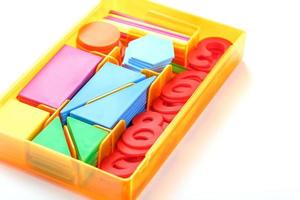 een doos met kleurrijk plastic figuren en getallen Aan een wit achtergrond. leerzaam spellen voor kinderen. foto