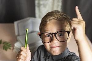 een slim jongen met bril enthousiast verhoogt zijn vinger omhoog, nieuw ontdekkingen, een enthousiast leerling met bril foto