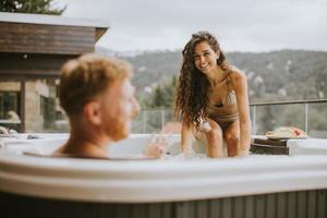 jong paar genieten van in buitenshuis heet kuip Aan vakantie foto