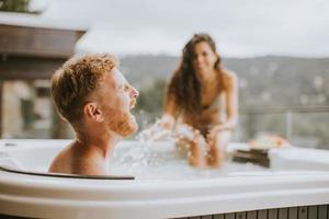 jong paar genieten van in buitenshuis heet kuip Aan vakantie foto