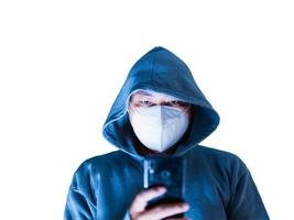 Aziatisch Mens in capuchon en masker hacken iets van een mobiel telefoon bedoeld naar nemen wazig foto's in een wit achtergrond. Daar is een knipsel pad. foto