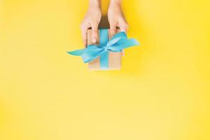 vrouw armen Holding geschenk doos met blauw lint Aan kleur achtergrond, top visie foto