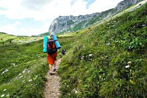 jong Kaukasisch vrouw wandelaar van achter met rugzak wandelen Aan een berg spoor Aan een achtergrond van groen vegetatie in de zomer in de Kaukasus bergen foto