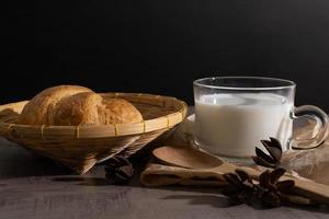 een reeks van croissant en kop van melk Aan de houten tafel foto