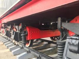 groot ijzer wielen van een rood en zwart trein staand Aan rails en suspensie elementen met veren van een oud industrieel stoom- locomotief foto