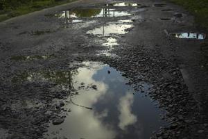 groot plas Aan asfalt. weg met kuilen. plassen Aan weg. foto