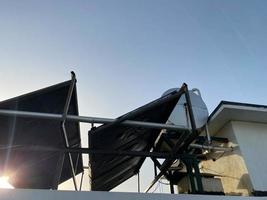 visie van de dak van een gebouw in een warm tropisch land met zonne- panelen en een water tank Aan de dak. energie doeltreffend milieuvriendelijk technologieën foto