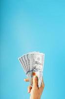 dichtproppen van bankbiljetten in hand- Aan een blauw achtergrond. de concept van financieel bijstand. foto