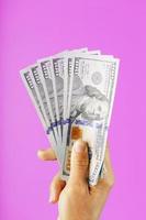 nieuw dollar rekeningen in hand- Aan een roze achtergrond. de concept van financieel bijstand. foto