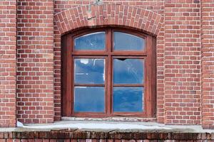 een gebogen glazen raam op oude rode bakstenen muur foto