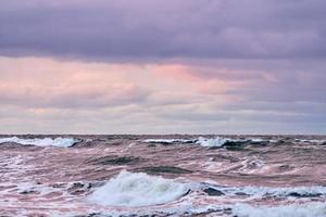 paarse bewolkte lucht en blauwe zee met schuimende golven, zeegezicht foto