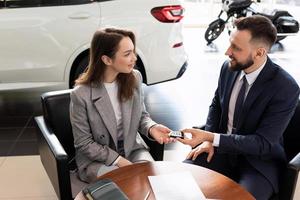 auto handel manager overhandigen over- sleutels naar nieuw auto koper. de concept van buying een auto Aan huren foto
