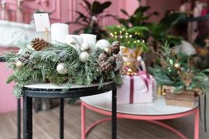 Kerstmis samenstelling van natuurlijk Spar met Kerstmis boom decoraties en cadeaus voor Kerstmis Aan een tafel in een elegant roze interieur foto