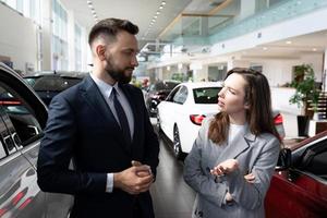 een jong vrouw in een auto handel is geïnteresseerd in de voorwaarden van een lening naar kopen een nieuw auto foto