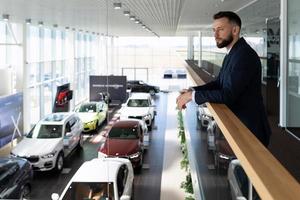 zakenman kiest een nieuw uitvoerend klasse auto in een handelaar toonzaal, concept auto leasing