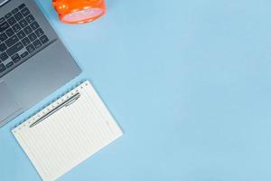 top visie van kantoor tafel top met laptop computer, oranje klok en notitieboekje met ruimte foto