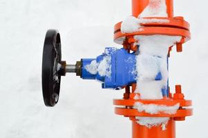 industrieel uitzetten regulerend beschermend pijp uitrusting. zwart klep voor opening, sluitend Aan een ijzer oranje metaal pijp met flenzen, studs, noten tegen de achtergrond van wit sneeuw in winter foto