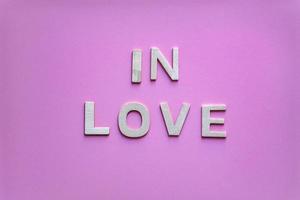 in liefde woord met houten brieven Aan de roze achtergrond, Valentijnsdag dag foto