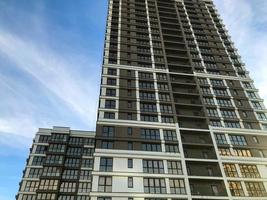 bruin en wit meerdere verdiepingen gebouw in de stad centrum. Daar is een klein gebouw De volgende naar de hoogbouw gebouw. overgang van huis naar huis langs de brug. tegen de blauw lucht foto