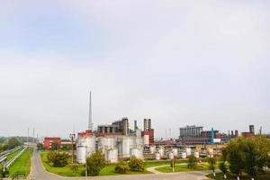 industrieel landschap, panoramisch visie van productie. chemisch planten, kolommen, generatoren, pijpen. olie behandeling systemen. gebouwen van productie. tegen de achtergrond van de bewolkt lucht en bomen foto