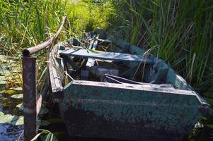 oud houten haveloos vervallen gebroken boot voor zwemmen Aan de banken van de rivier, meer, zee in de gras en riet in natuur foto