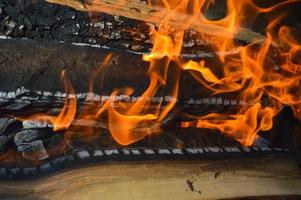 houten brandend heet verkoold planken van hout logboeken in een brand met tongen van brand en rook. textuur, achtergrond foto