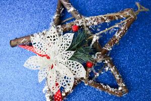 groot decoratief mooi houten Kerstmis ster, een zelf gemaakt komst krans van Spar takken en stokjes Aan de feestelijk nieuw jaar gelukkig blauw glimmend blij achtergrond. vakantie decoraties foto