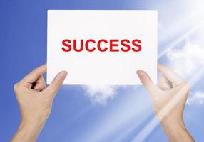 zakenman hand- Holding wit papier en woord succes Aan blauw lucht achtergrond foto
