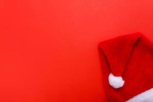 de kerstman hoed Aan rood Kerstmis achtergrond met kopiëren ruimte voor tekst. foto