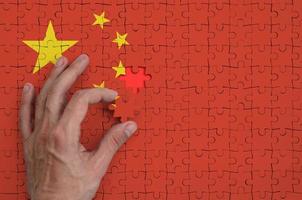 China vlag is afgebeeld Aan een puzzel, welke de man's hand- voltooit naar vouwen foto