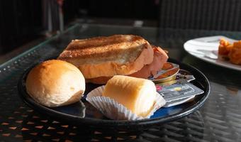 plakjes van brood, broodje, jam rollen en boter voor ontbijt foto