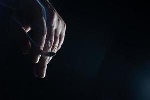een bijgesneden van Mens hand- Holding sigaret zwart achtergrond foto
